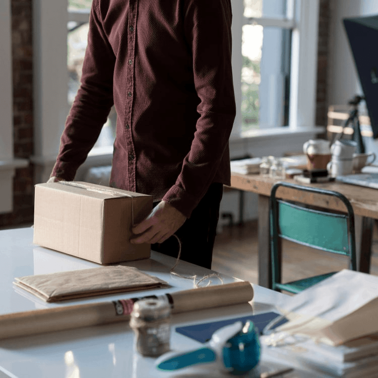 Close up shot of a man packing a package in a carboard box.