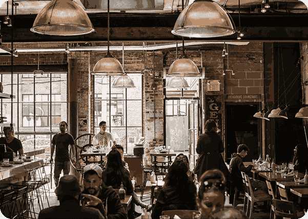 A cozy industrial-style café with patrons enjoying their meals under warm lighting.