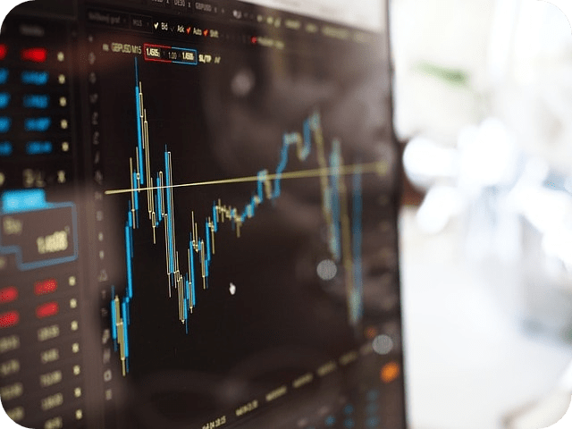 A close-up view of a computer screen displaying a financial stock chart with fluctuating candlestick data and indicators, representing market analysis or trading activity.